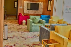 ein Wohnzimmer mit bunten Stühlen und einem TV in der Unterkunft ركن الباهية للشقق المخدومة - مخرج 9 in Riad