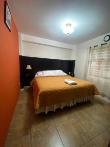 ein Schlafzimmer mit einem Bett mit einer orangefarbenen Decke in der Unterkunft Apartamento #1 Portal de Occidente in Quetzaltenango