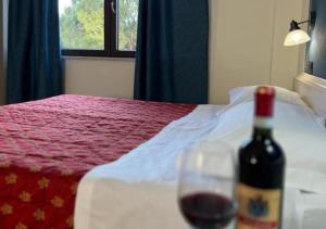 a bottle of wine sitting on a table next to a bed at Il Grifo Hotel e Bisteccheria Toscana in Montepulciano