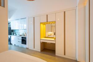a kitchen with white cabinets and a yellow mirror at Voyage Studio In Mayan With Partial Ocean Views in Abu Dhabi