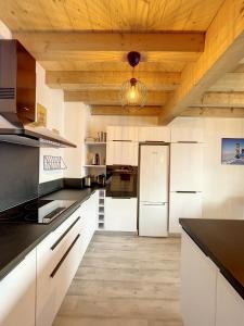 a kitchen with white cabinets and a wooden ceiling at Chalet Le Vallonnet in La Toussuire