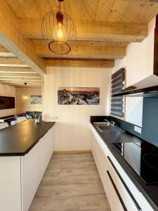 eine Küche mit schwarzen Arbeitsplatten und Holzdecken in der Unterkunft Chalet Le Vallonnet in La Toussuire