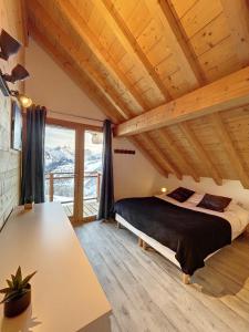 sypialnia z łóżkiem i dużym oknem w obiekcie Chalet Le Vallonnet w mieście La Toussuire
