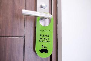 a door handle with a sign that says please do not disturb at Urbanview Grand Lotus Hotel by RedDoorz in Purwokerto