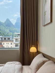a bedroom with a bed and a window with a view at Pomelo Hostel in Yangshuo