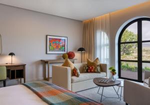 The Hazendal Hotel by NEWMARK في ستيلينبوش: غرفة معيشة مع سرير وأريكة