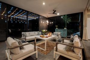un patio con mesa, sillas y luces en Open House by StayVista - Nestled in nature, featuring a Swimming pool & Expansive lawn for a serene retreat, en Shikrapur