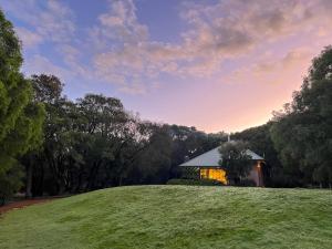 a house on a grassy hill with a building at Waterfall Cottages in Margaret River Town