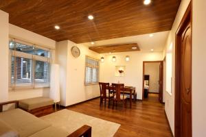 a living room with a table and a dining room at Green Wood Hill Cottage in Ooty
