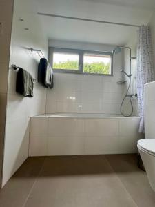 een witte badkamer met een bad en een raam bij Appartement Huis op het Duin in Egmond aan Zee