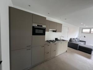 a kitchen with stainless steel appliances and a couch at Appartement Huis op het Duin in Egmond aan Zee