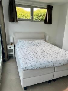 białe łóżko w sypialni z oknem w obiekcie Appartement Huis op het Duin w mieście Egmond aan Zee