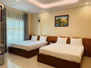 a hotel room with two beds and a window at Đà Lạt Hotel in Mỹ Hào