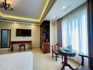 a room with a bed and a table and a television at Đà Lạt Hotel in Mỹ Hào