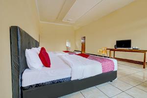 1 dormitorio con 1 cama grande con sábanas blancas y almohadas rojas en OYO 92217 Artana Bed and Breakfast en Pengalongan