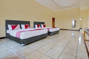 2 camas en un dormitorio con almohadas rojas y blancas en OYO 92217 Artana Bed and Breakfast en Pengalongan
