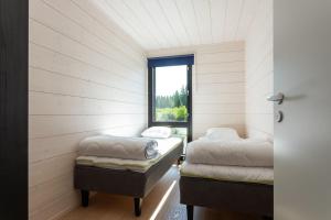 two beds in a room with a window at Himoskuutio 8, erillistalo, ulkoporeallas in Jämsä