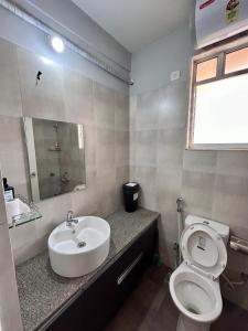 a bathroom with a sink and a toilet and a mirror at Good Stay Premium 2 BHK Apartment 103 in Vasco Da Gama