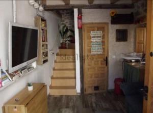 uma sala de estar com televisão e escadas com porta em Casita con encanto tranquilidad VILLAVIEJA DEL LOZOYA Wi-Fi No fumador EN SIERRA DE MADRID Y A 40 M DE CAPITAL em Villavieja del Lozoya