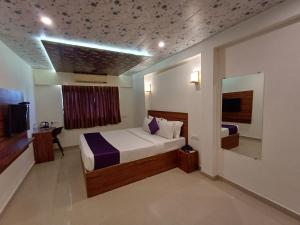 a hotel room with a bed and a window and a television at VITS Daman Devka Beach in Daman