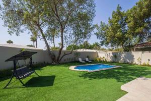 a backyard with a swimming pool and a swing at Nordic Gardens in Manama