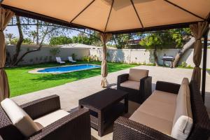 a patio with chairs and an umbrella and a pool at Nordic Gardens in Manama