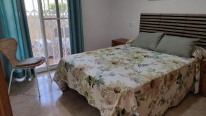a bedroom with a bed with a floral bedspread at Apartamento con piscina y cerca de la playa in Canet de Berenguer