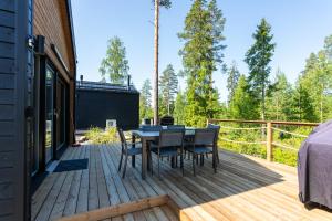 une terrasse en bois avec une table et des chaises. dans l'établissement Himoskuutio 9, erillistalo, ulkoporeallas, à Jämsä