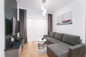 a living room with a couch and a television at Apartament Marengo Ku Morzu by HolidaySun in Sianozety