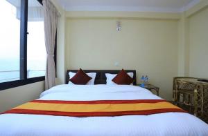 een slaapkamer met een groot wit bed met rode kussens bij Hotel Bihani in Dhulikhel