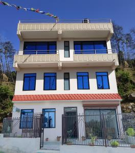 a large white building with blue windows at Hotel Bihani in Dhulikhel