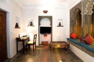 a living room with a couch and a desk and a tv at Madri Haveli in Udaipur