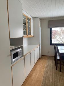 une cuisine avec des placards blancs et une table avec un four micro-ondes dans l'établissement Villa Tatu, à Rovaniemi