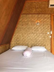 ein Bett mit zwei Kissen in einem Zimmer in der Unterkunft Muni's Terrace Bungalow in Kotaraja