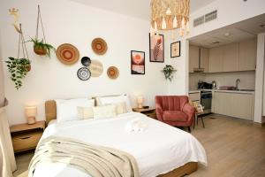 une chambre avec un grand lit blanc et une chaise rouge dans l'établissement Vali Haven - Cozy Studio Retreat on Yas Island, Near Yas Mall, à Abu Dhabi