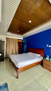 um quarto com uma cama grande e uma parede azul em Villa Copenhagen Bukittinggi em Bukittinggi