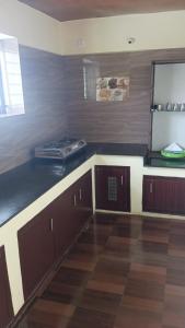 a kitchen with wooden cabinets and a counter top at FLGHR Green Star Bungalow in Kodaikānāl