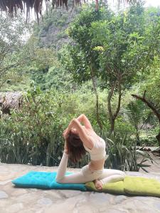 une femme faisant une pose de yoga sur un tapis de yoga dans l'établissement Thung Sen Tam Coc Chalets, à Ninh Binh