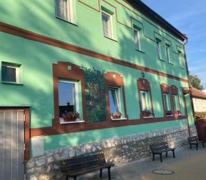 zielony budynek z oknami i ławką w obiekcie Penzion Romeo w mieście Mladeč