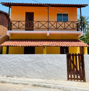 a yellow and white house with a gate at Casa Ariacó in Amontada