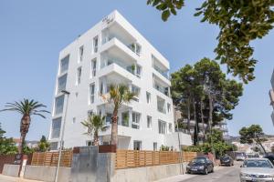 a white building with palm trees in front of it at Vista Roses Mar - Vent De Mar in Roses