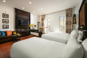 a bedroom with two white beds and a television at The Silk Boutique Hotel & Spa - Old Quarter City Center in Hanoi