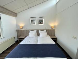 ウフストヘーストにあるLandgoed Oud Poelgeest - Leidenのテーブル2台付きの客室で、白い大型ベッド1台が備わります。