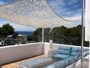 a patio with a blue couch and an umbrella at 5 bedroom villa in Cala Vadella in Sant Josep de Sa Talaia
