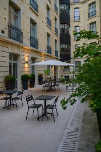 un patio extérieur avec des tables, des chaises et des parasols dans l'établissement La Clef Champs-Élysées Paris by The Crest Collection, à Paris