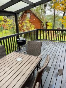 una terrazza in legno con griglia e sedie. di Domek całoroczny HAWAJE nad jeziorem Kazub a Cieciorka