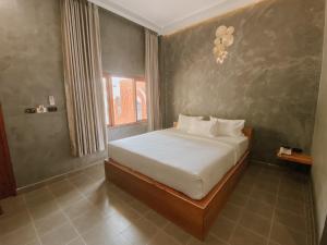 um quarto com uma cama com lençóis brancos e uma janela em Tachang Airport Hotel em Hat Yai