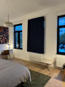 een slaapkamer met een bed en een tafel en ramen bij Astrid in Mechelen