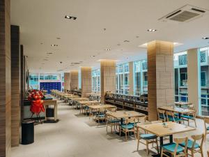 - une salle à manger avec des tables, des chaises et des fenêtres dans l'établissement ASTON Nagoya City Hotel, à Batam Center