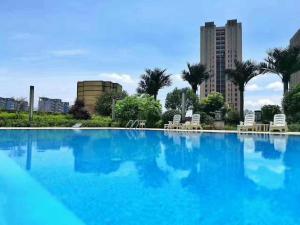una grande piscina blu con sedie e edifici di WorldHotel Grand Jiaxing Hunan a Changsha